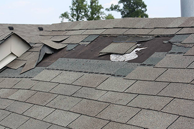 Damaged patch on roof with shingles missing due to weather.